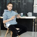 Teenager in casual outfit studying online at home using a tablet.