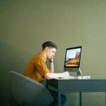 Man focused on work at home office desk with computer, displaying concentration and modern workspace.